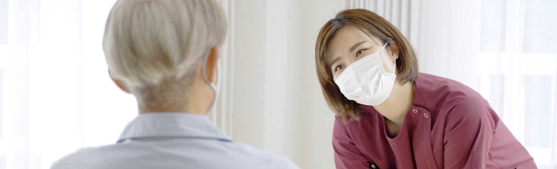 Support worker wearing mask looking kindly at resident in mask